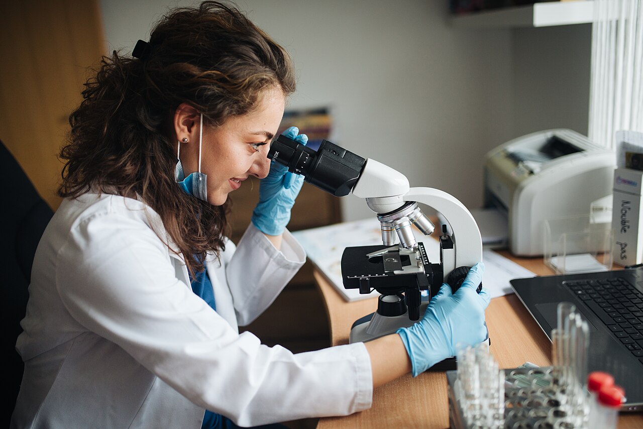 Lab technitian looking through the microscope while adjusting coarse knob