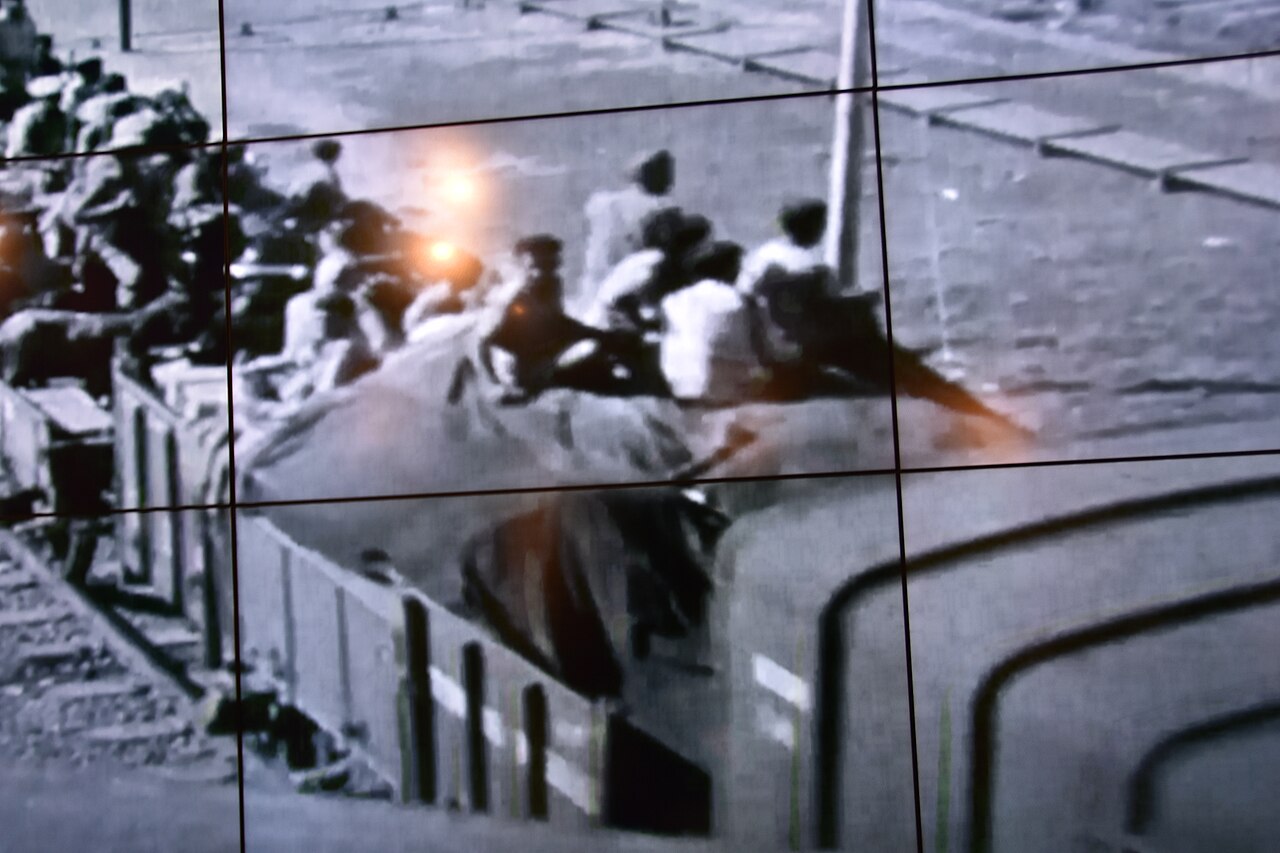 A movie running in a continuous loop shows a freight train packed with desperate people on a run between India and Pakistan. (or vice versa). Massive