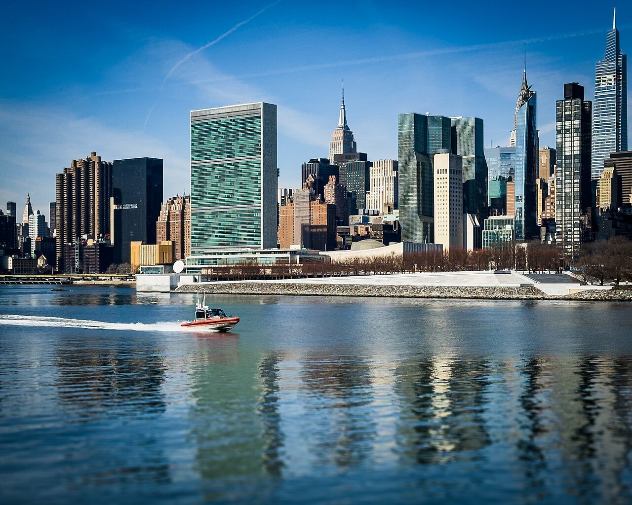 Boat passing United Nations Headquarters and surrounds, seen from the East River